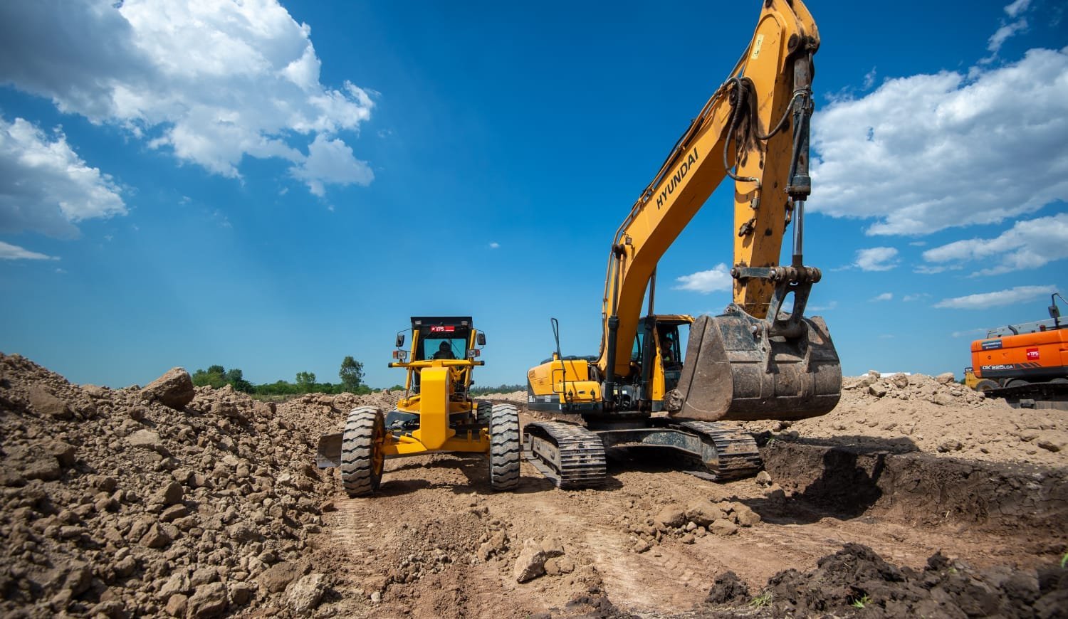 Excavadora y motoniveladora en movimiento de suelos