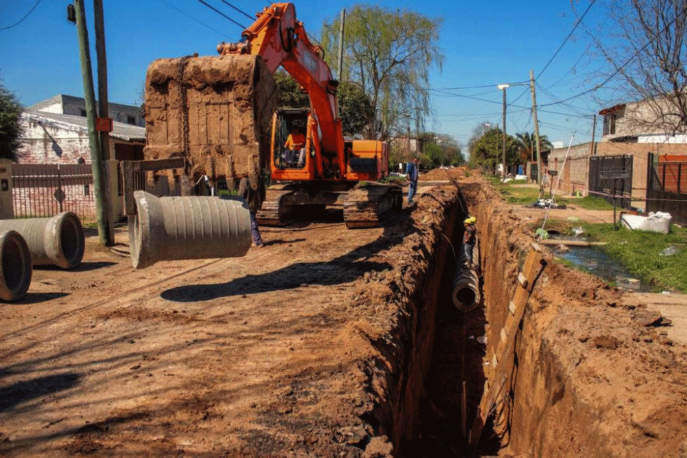 Excavadora colocando caÃ±os de hormigÃ³n en zanja para tendido cloacal